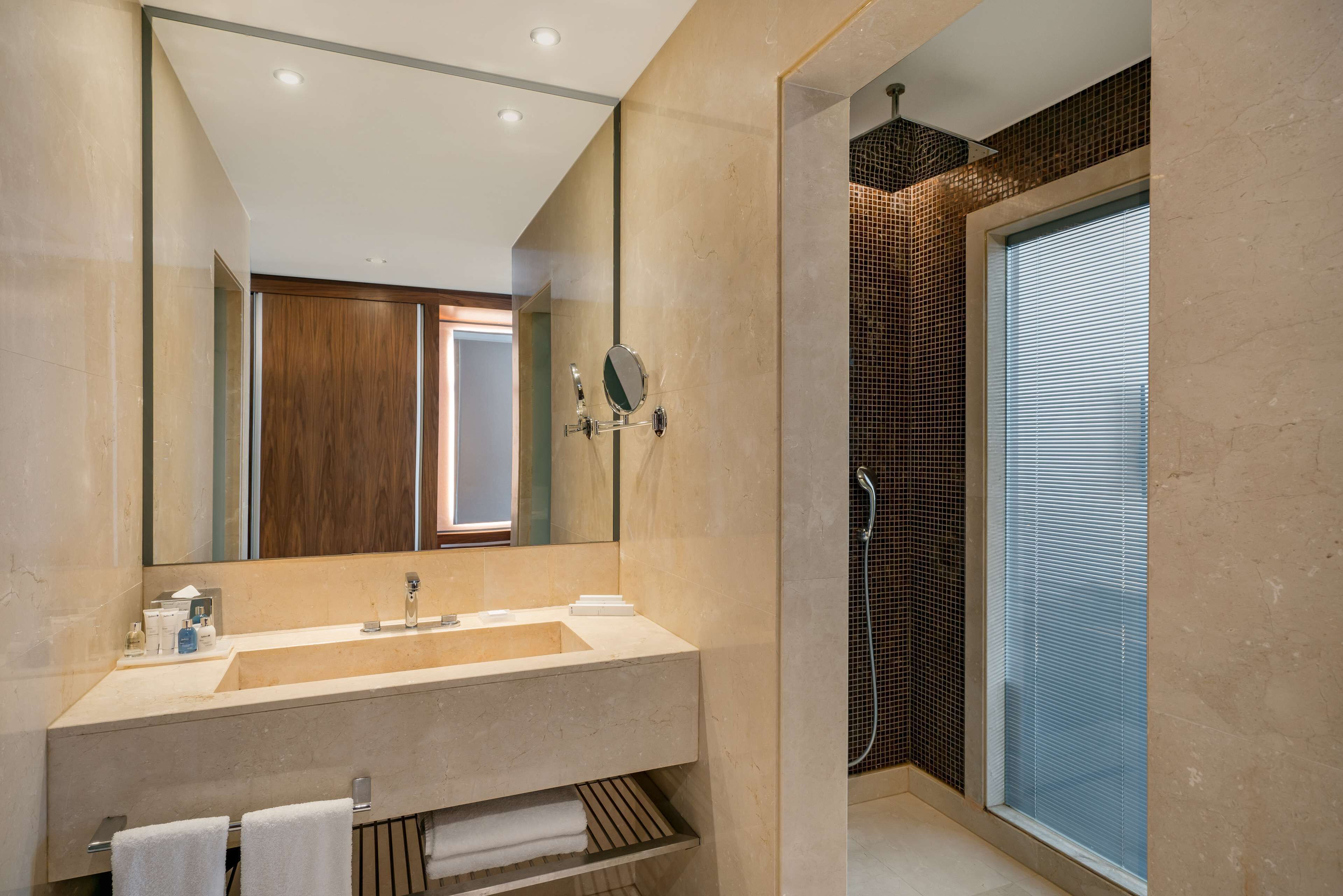 Un baño moderno con un espejo grande, un lavamanos y una zona de ducha.