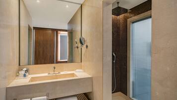 Un baño moderno con un espejo grande, un lavamanos y una zona de ducha.
