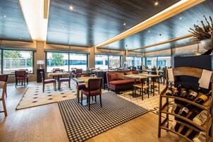 Un amplio vestíbulo de hotel con varias zonas de estar, una bodega de vinos y grandes ventanales que ofrecen vistas al exterior.