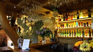 A bar area with a wooden ceiling, hanging wine glasses, and shelves of various liquor bottles. - Pensjonat u Ani (Zakopane)