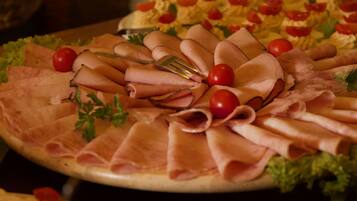 A platter of sliced meats and tomatoes on a wooden board.