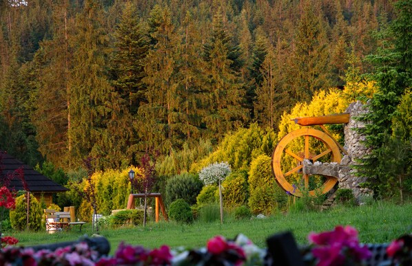 A garden with a wooden wheel, benches, and a small building.