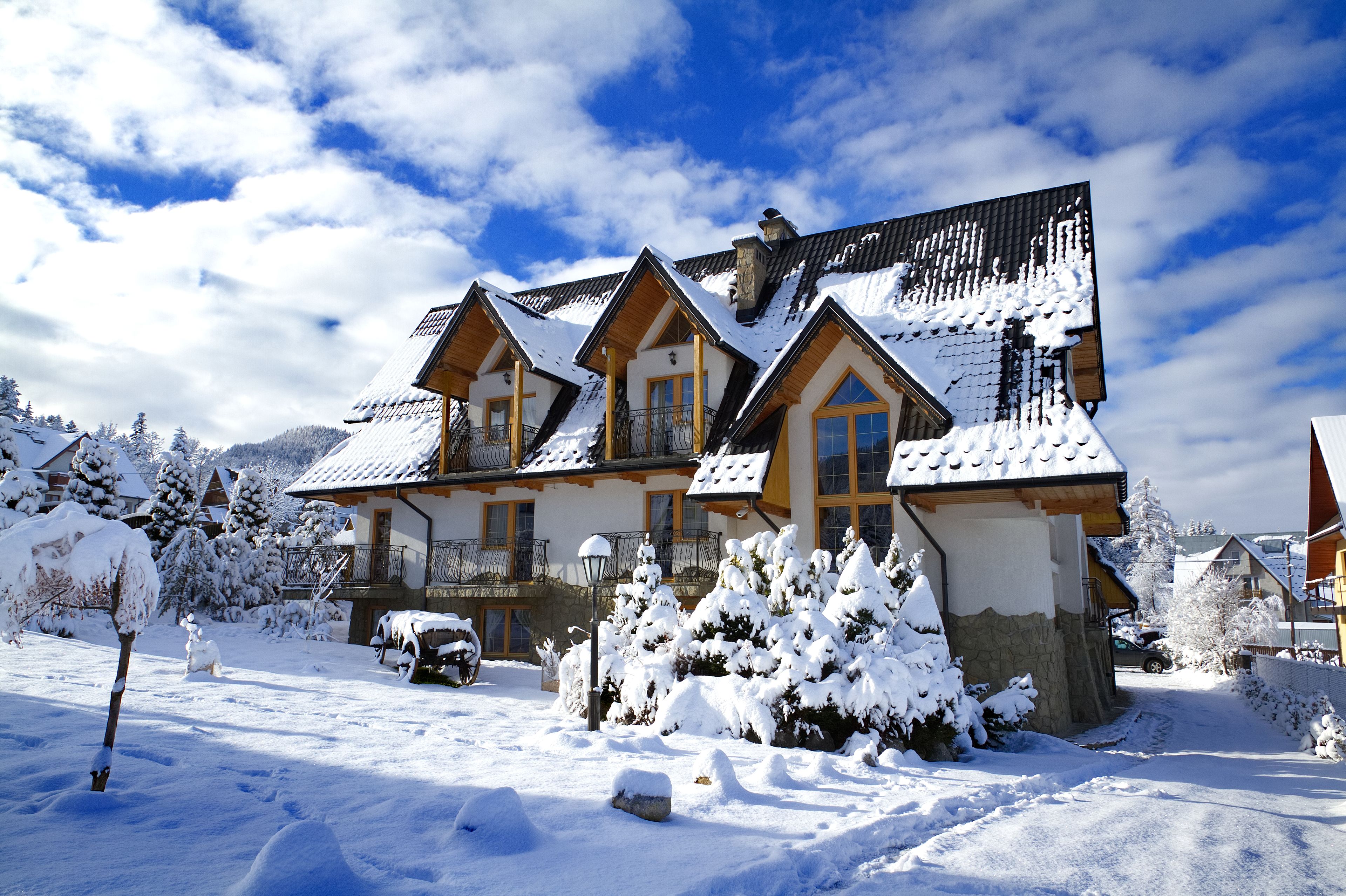 A snow-covered lodge with multiple balconies and a mountain backdrop.