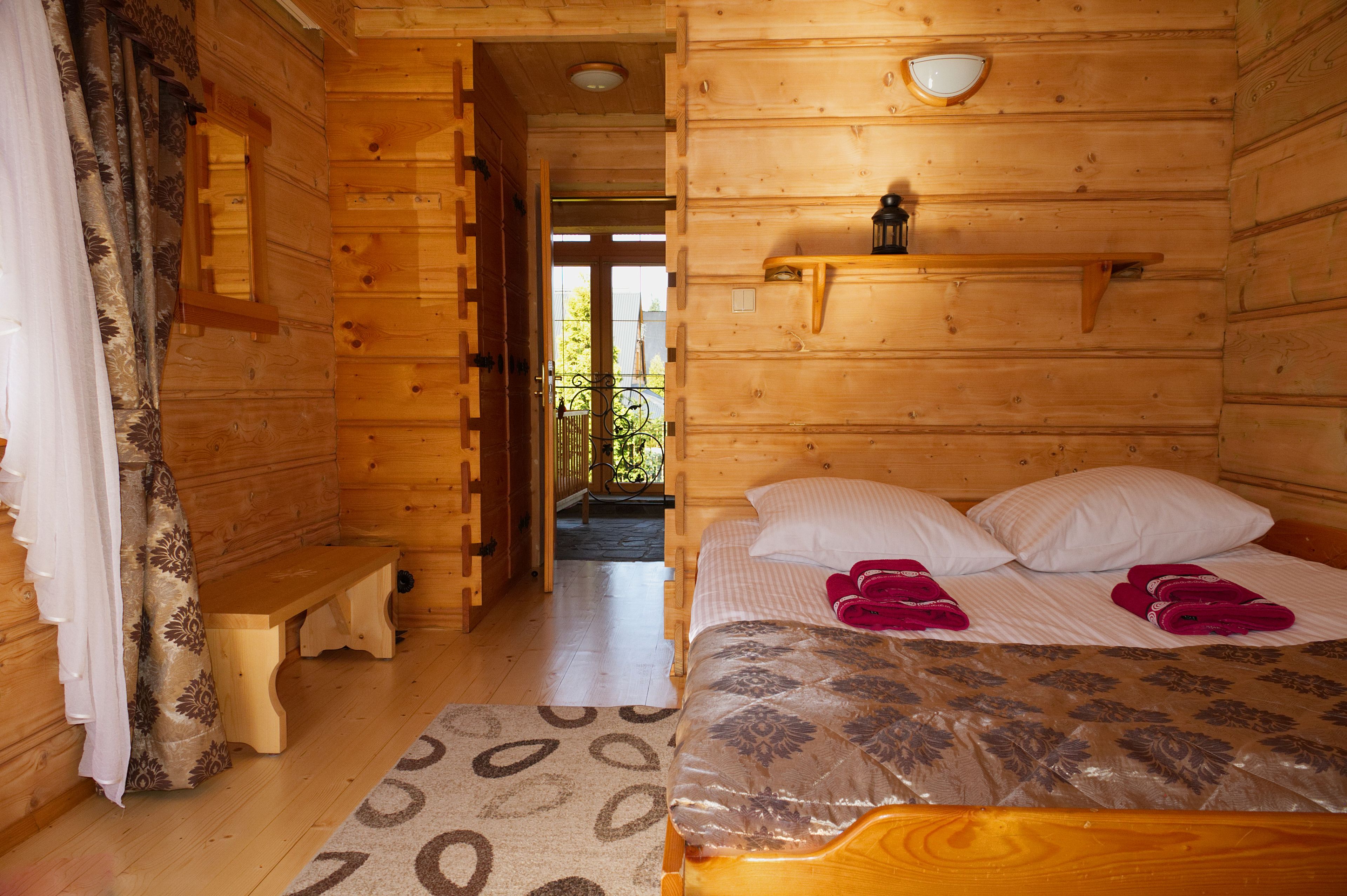 Habitación de cabaña de madera con cama, banco y una pequeña mesa.