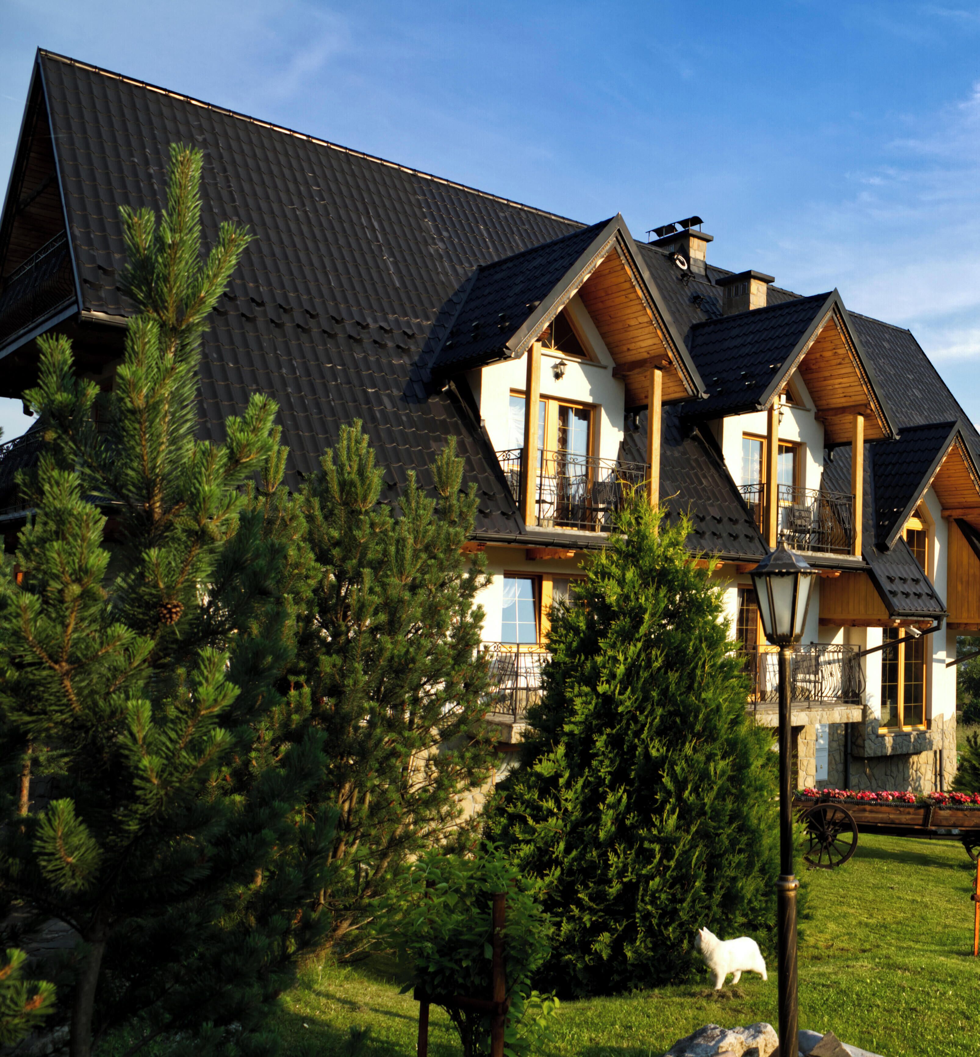 A multi-story building with a sloped roof, wooden balconies, and a well-maintained garden.