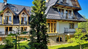A large, multi-story house with a stone facade, multiple balconies with wrought iron railings, and a well-maintained garden. - Pensjonat u Ani (Zakopane)