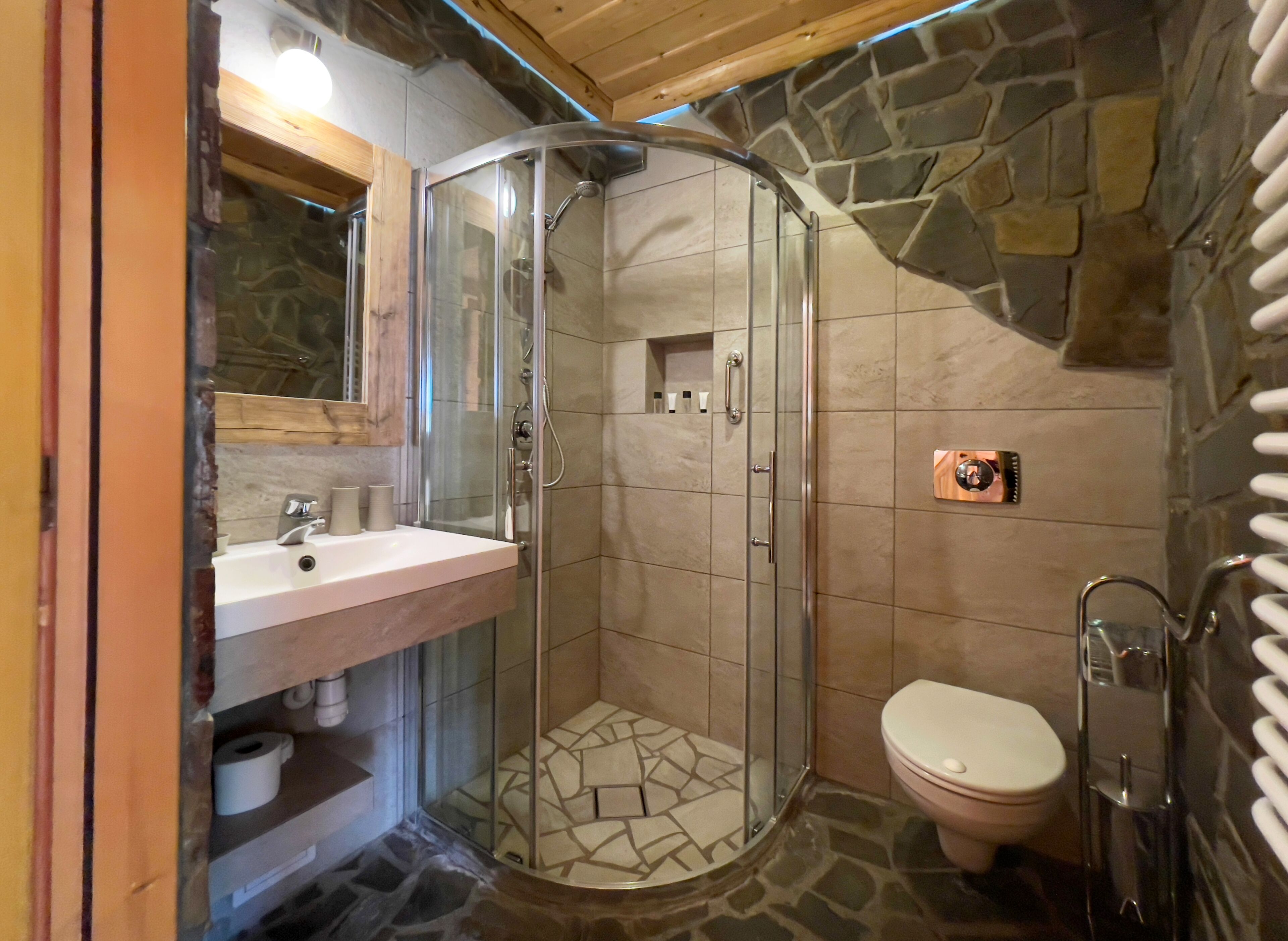 A bathroom with a glass-enclosed shower, a sink with a mirror, and a toilet.