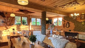 A rustic wooden interior with a long dining table, benches, and a fireplace. - Pensjonat u Ani (Zakopane)