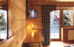 A wooden cabin interior with a wooden bench, a mounted television, and a window with a view of a snowy landscape. - Pensjonat u Ani (Zakopane)