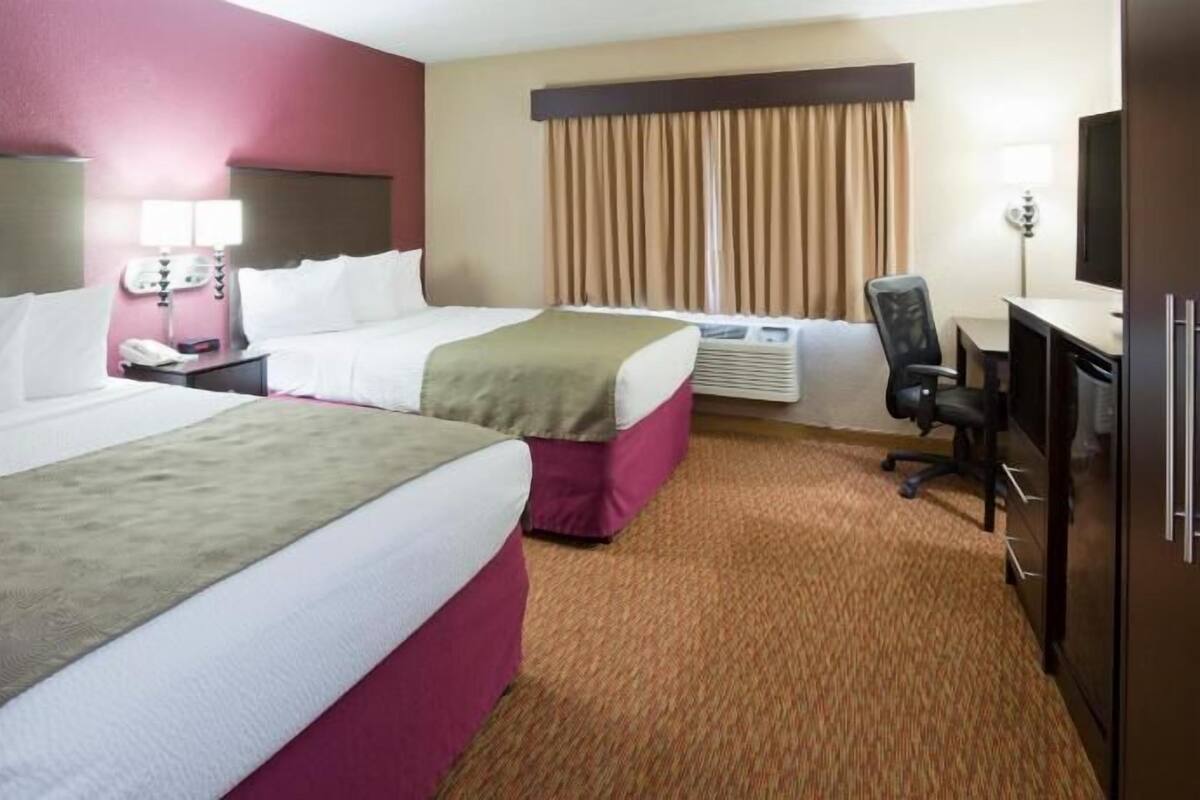 Une chambre d’hôtel avec deux lits, un bureau, une chaise, un téléphone et un appareil de climatisation.