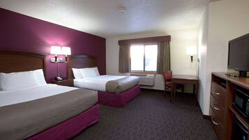 A hotel room with two beds, a desk, a chair, a TV, and a window with curtains.