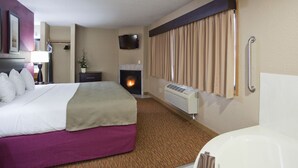 Een hotelkamer met een bed, een open haard, een televisie en een badkamer met een bad.