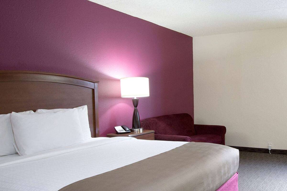 Une chambre d’hôtel avec un lit, une table de chevet, une lampe et une chaise.