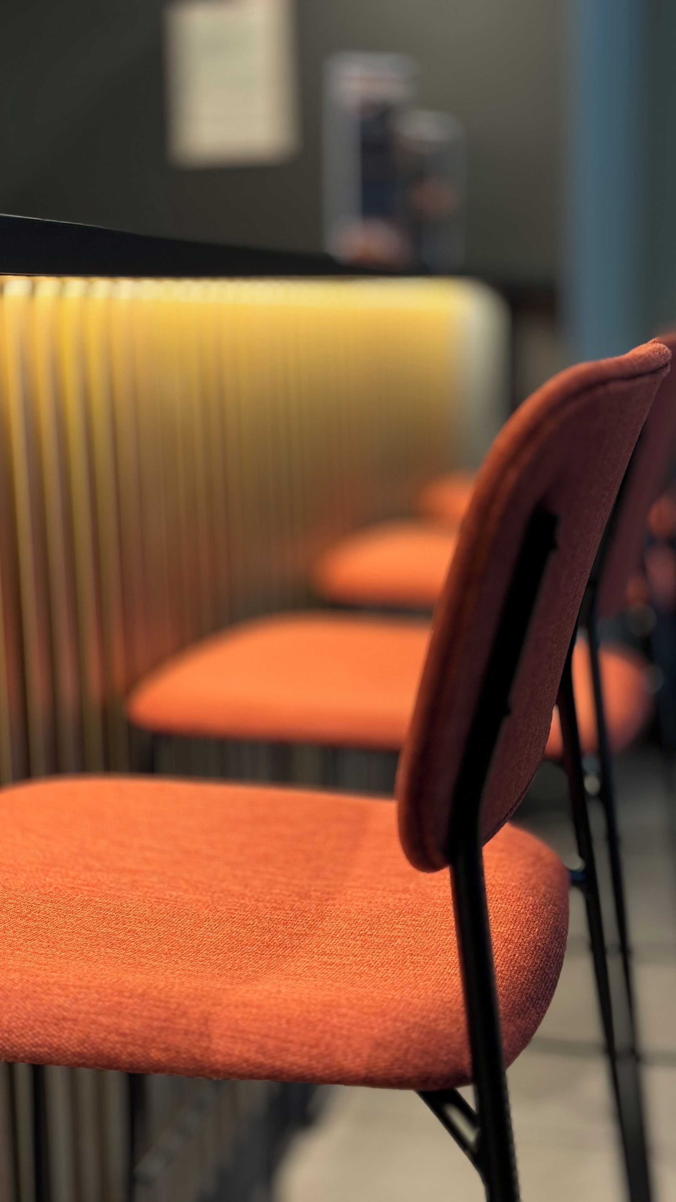 A row of orange chairs with black metal frames, arranged in a row.