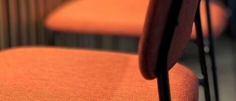 A row of orange chairs with black metal frames, arranged in a row.