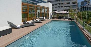 Una piscina al aire libre de temporada, sombrillas