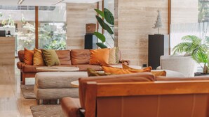 Un vestíbul modern amb un sofà de cuir, una taula de cafè rodona i una planta en test.