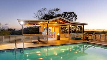 Una piscina al aire libre, sombrillas, sillones reclinables de piscina