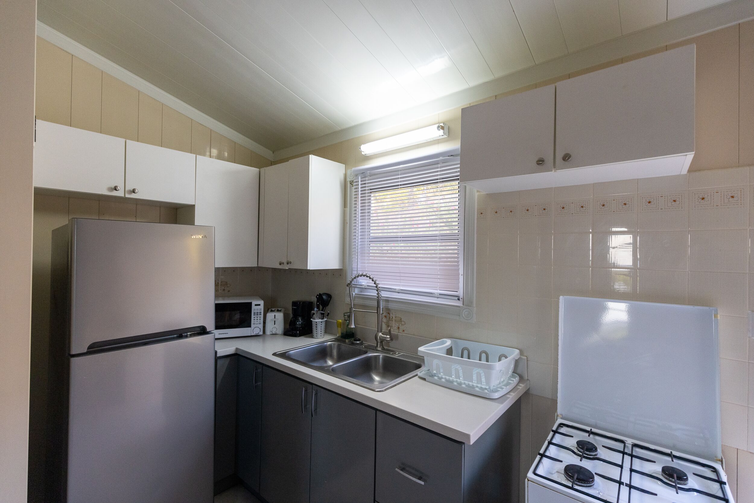 A kitchen with a refrigerator, microwave, sink, and stove.