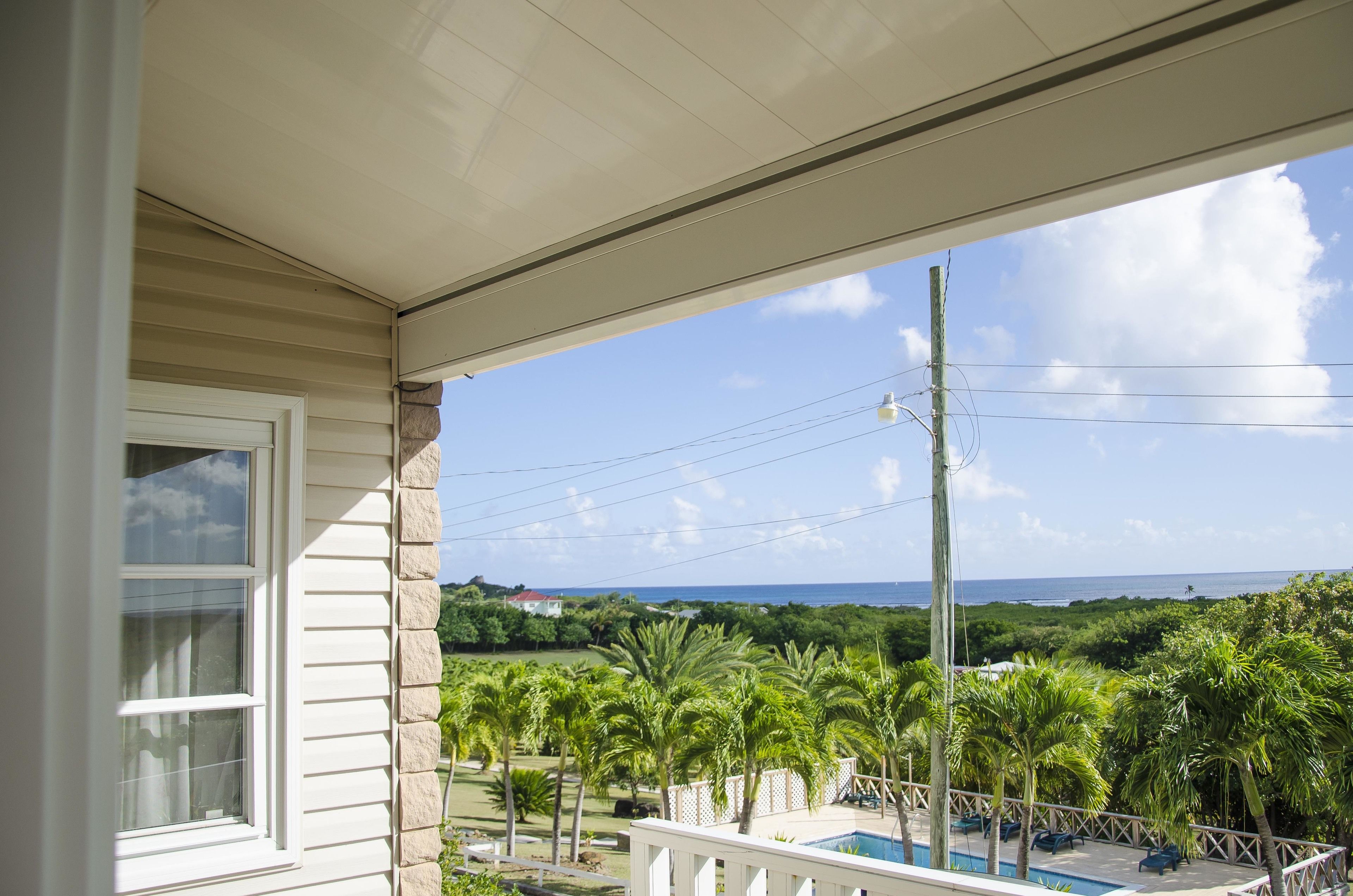 A balcony with a view of the ocean and palm trees.