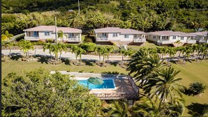 Zona residencial con tres casas, piscina y palmeras.