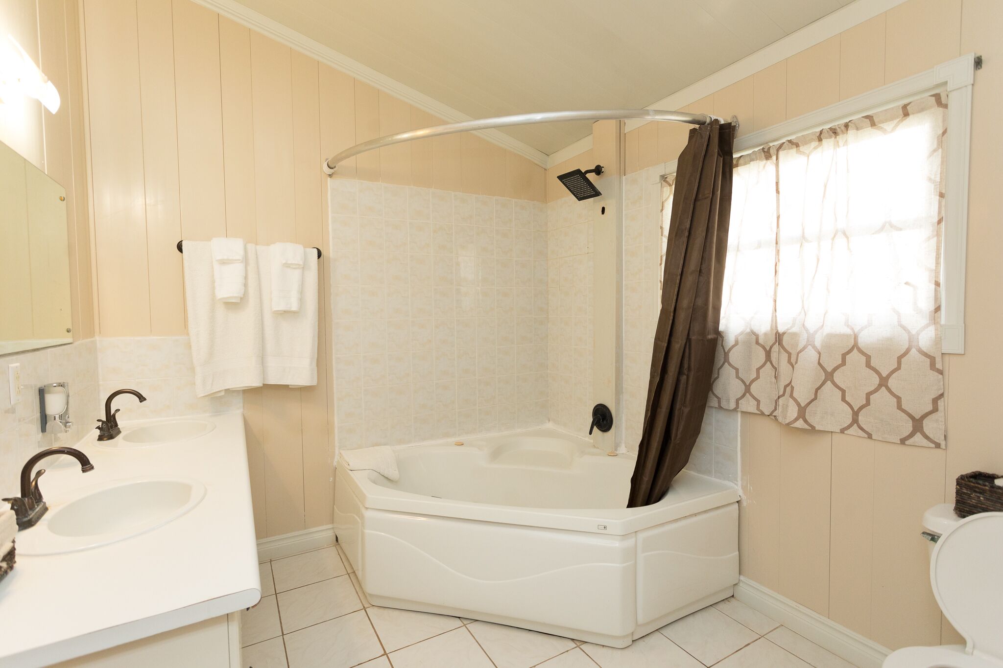 A bathroom with a bathtub, two sinks, a toilet, and a shower curtain.