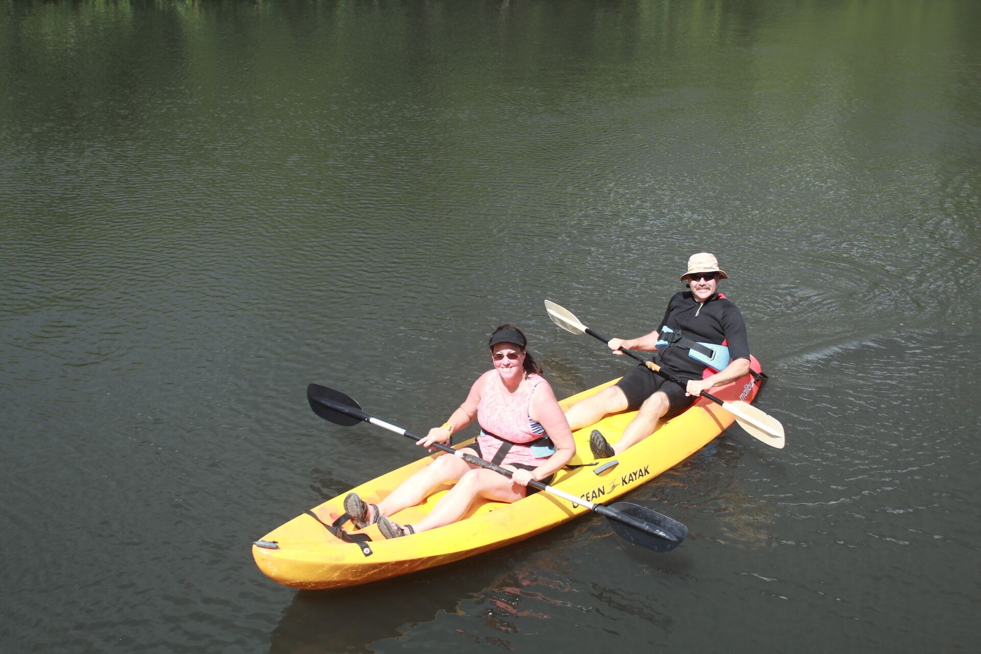 Two people kayaking on a calm body of water.