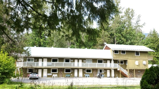 A two-story building with a balcony, a staircase, and a parking area. - The Hitching Post Motel (Mount Currie)
