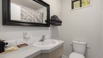 A bathroom with a white sink, a mirror, a toilet, and a window.