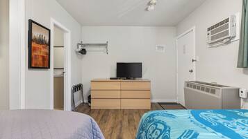 A bedroom with a bed, a dresser, a television, a radiator, and a door.