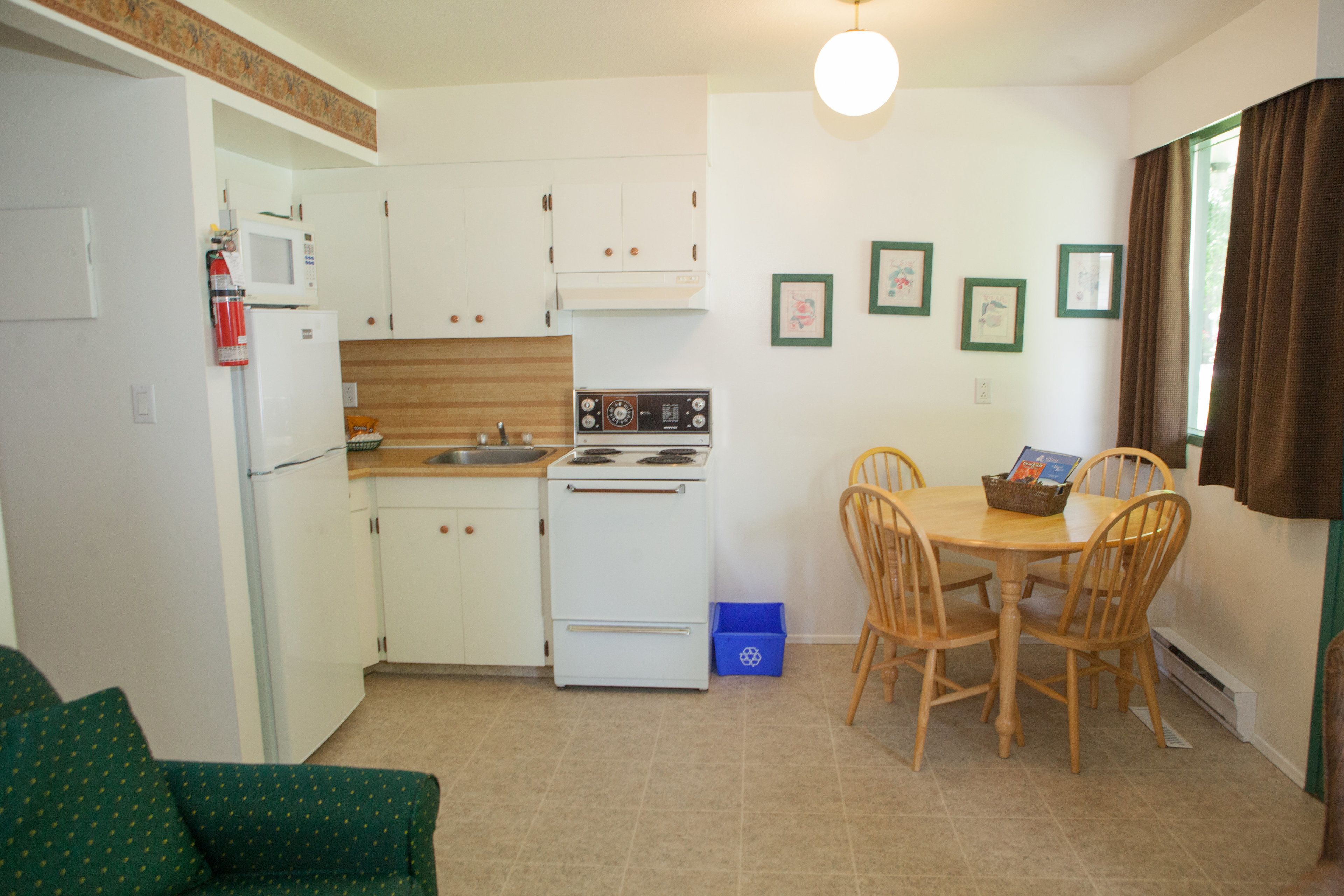 A compact kitchen with white cabinets, a microwave, a stove, and a dining table with chairs.