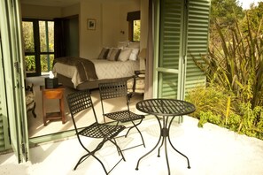 Un dormitorio de concepto abierto con una cama, dos sillas, una mesita y vistas al exterior.