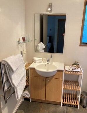 Un baño moderno con un lavamanos grande, tocador de madera y un espejo.