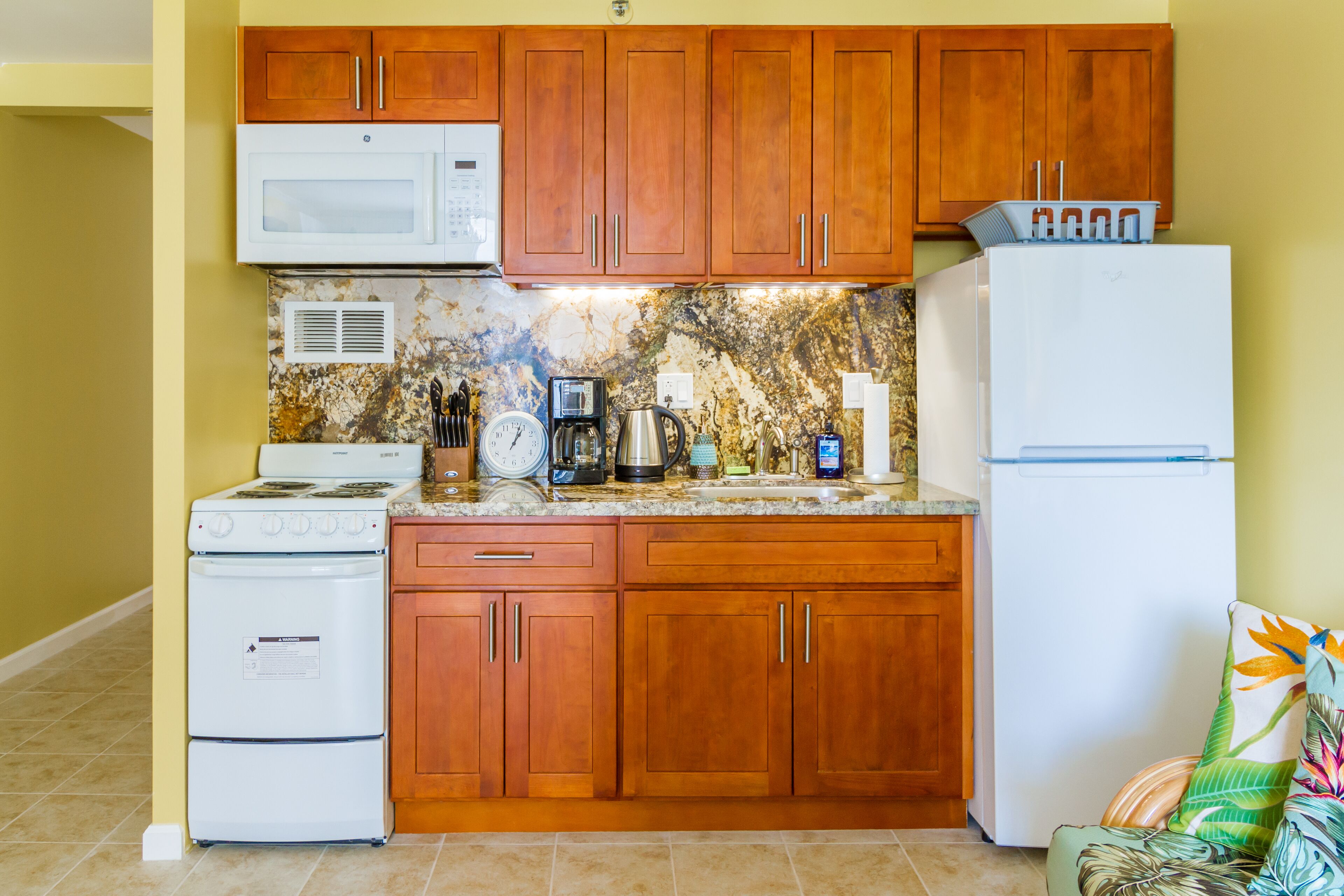 A kitchen with wooden cabinets, a microwave, a stove, a refrigerator, and a coffee maker.