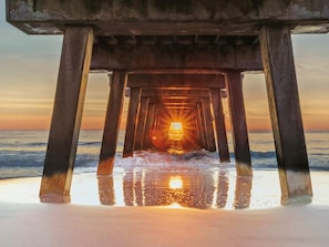 A pier structure with a sunset view through its open end.