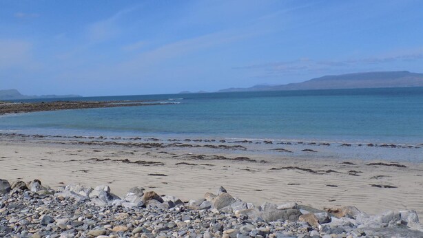A beach with pebbles and a rocky shoreline.