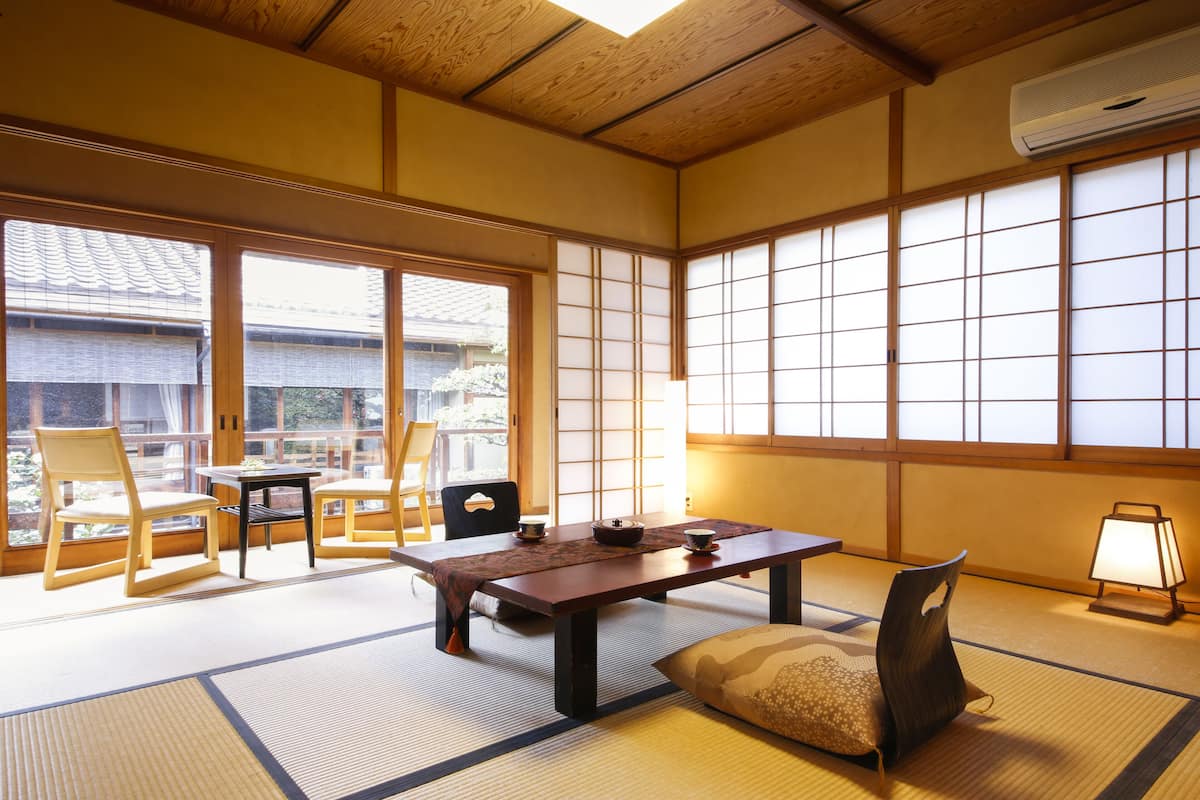 Una habitación japonesa tradicional con suelo de tatami, una mesa baja y paneles shoji.