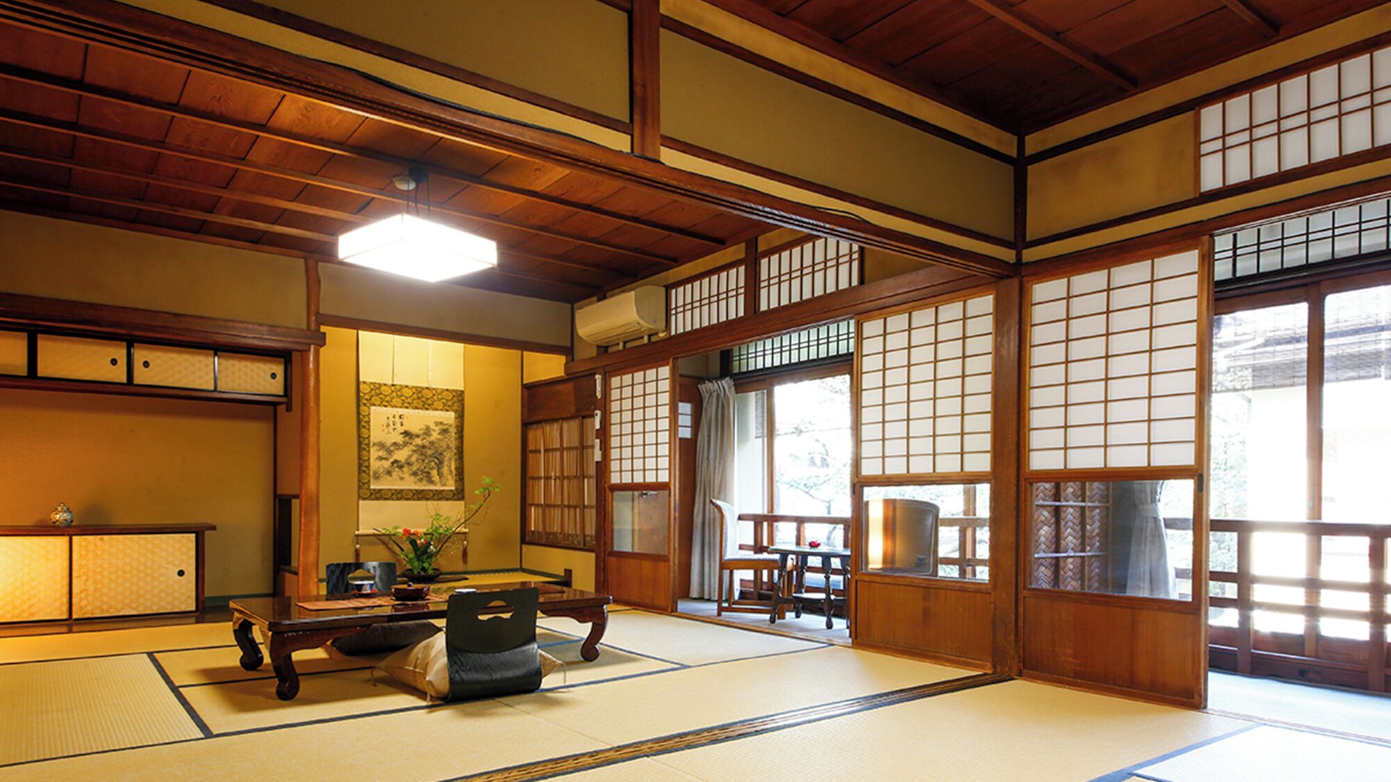 A traditional Japanese room with tatami flooring, a low table, a bench, and sliding doors with shoji screens.
