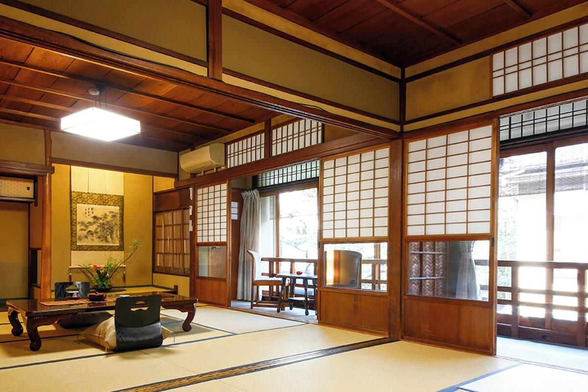 A traditional Japanese room with tatami flooring, a low table, a bench, and sliding doors with shoji screens.