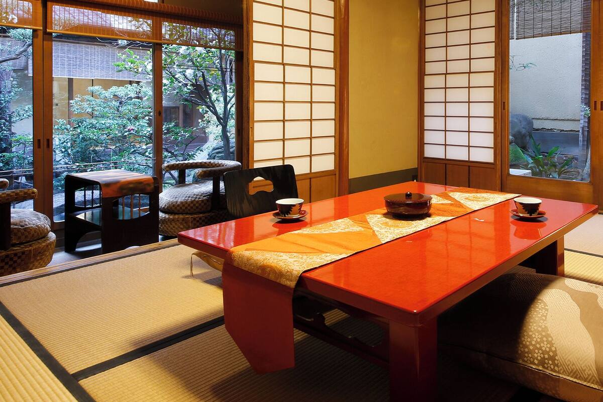 Una habitación japonesa tradicional con suelo de tatami, una mesa baja y puertas correderas shoji.