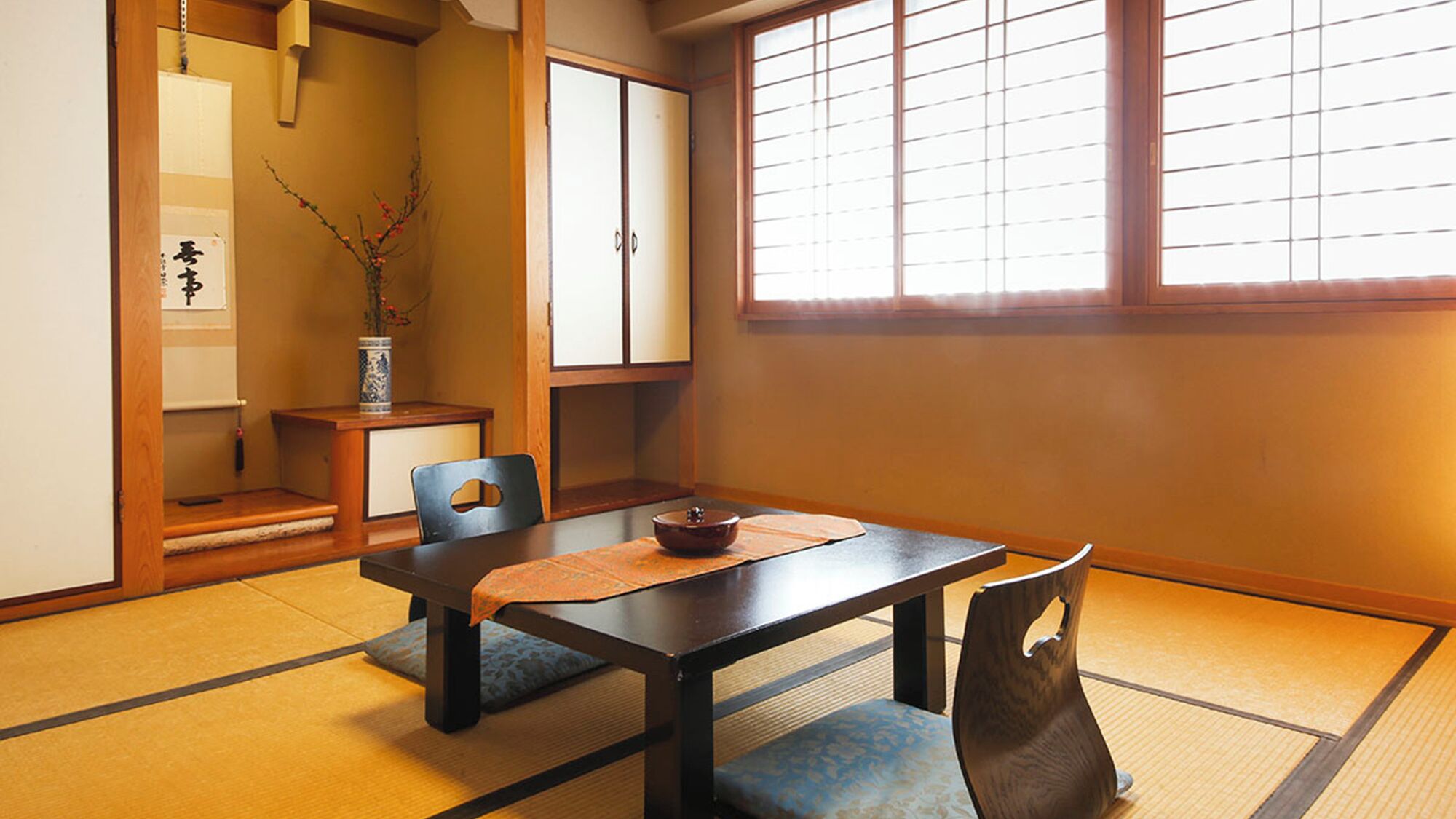 A traditional Japanese room with tatami flooring, a low table, and sliding doors.