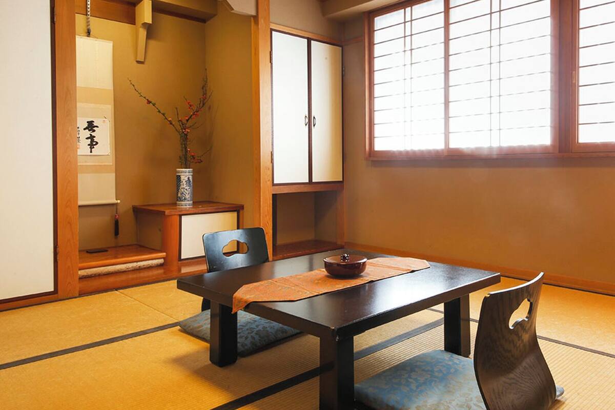 Una habitación japonesa tradicional con suelo de tatami, una mesa baja y puertas correderas.
