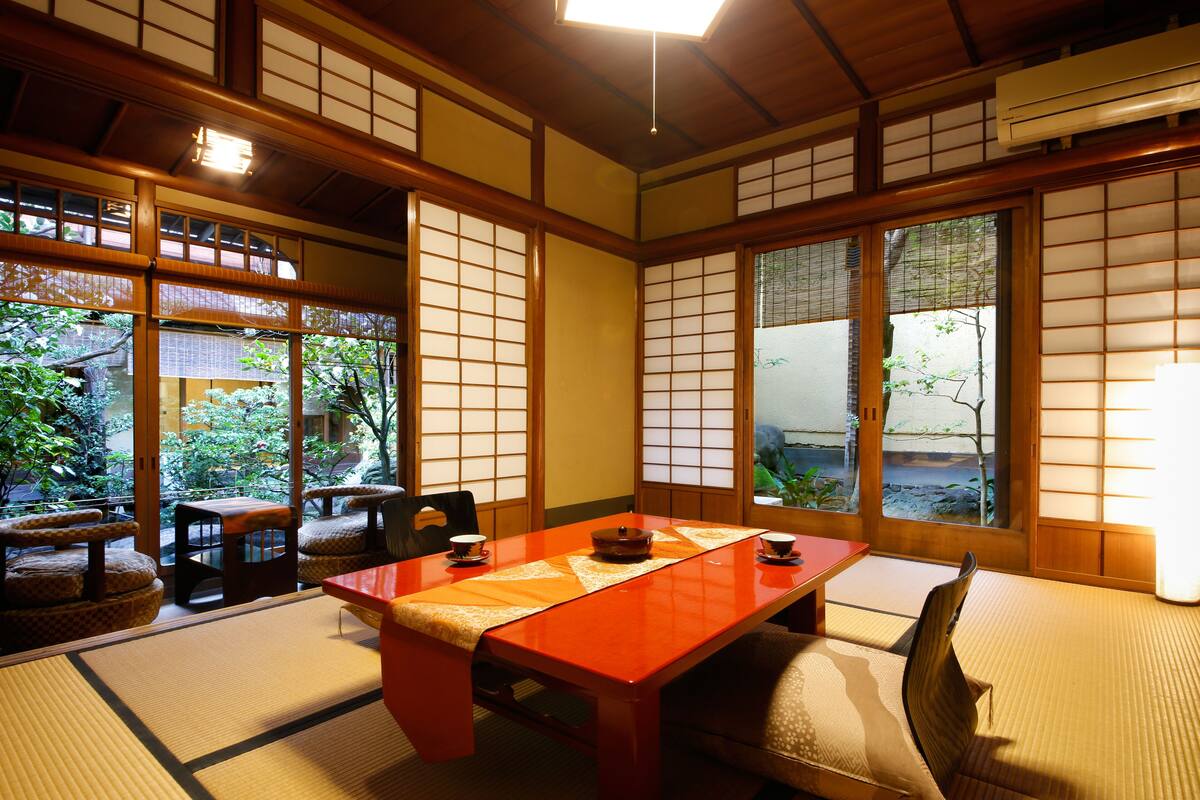Una habitación japonesa tradicional con suelo de tatami, una mesa baja y puertas correderas.