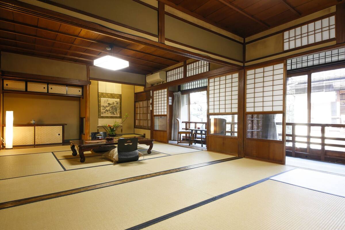 Una habitación japonesa tradicional con suelo de tatami, puertas correderas y techo bajo.