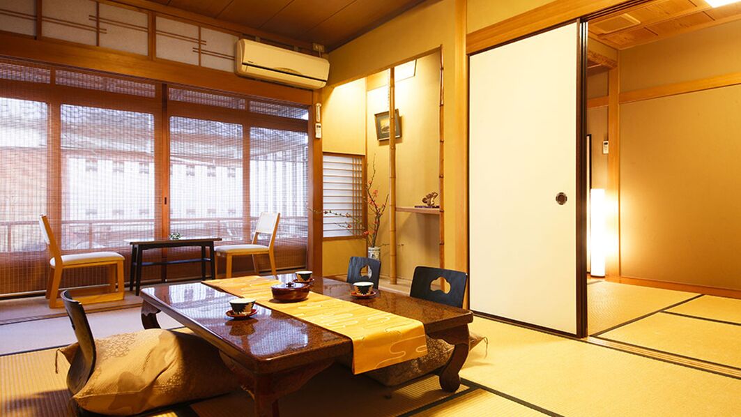 A traditional Japanese room with tatami flooring, a low table with a yellow mat, and sliding doors.