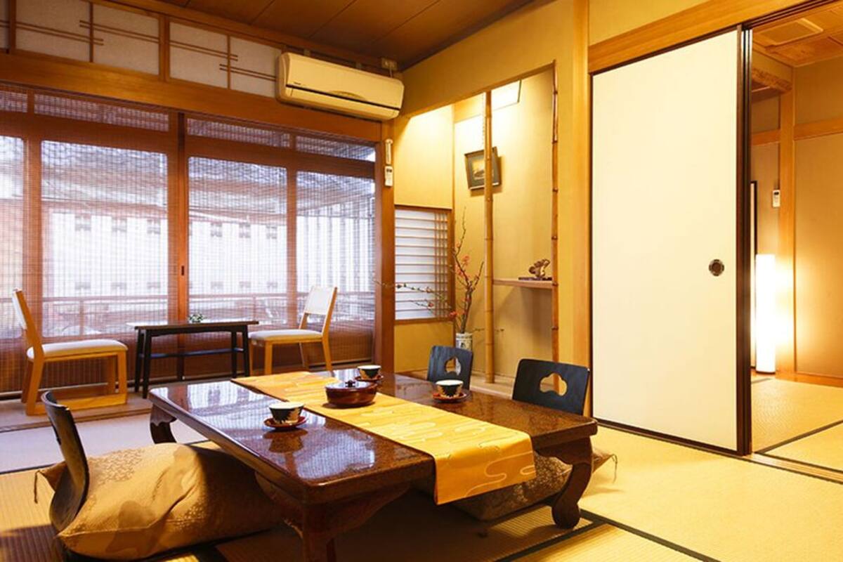A traditional Japanese room with tatami flooring, a low table with a yellow mat, and sliding doors.