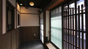 A narrow corridor with wooden paneling and a sliding door with a metal grid. - Azuki-an Machiya Holiday House (Kyoto)