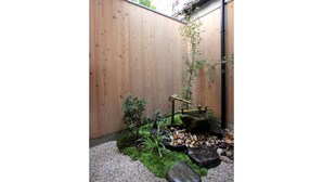 A wooden fence, a small garden with rocks, and a water feature. - Azuki-an Machiya Holiday House (Kyoto)