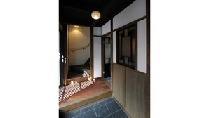 A traditional Japanese interior with tatami flooring, a wooden staircase, and a shoji screen door. - Azuki-an Machiya Holiday House (Kyoto)