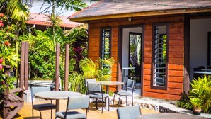 A wooden building with a tiled roof, surrounded by lush greenery and outdoor seating. - Eden's Edge Hotel (Apia)